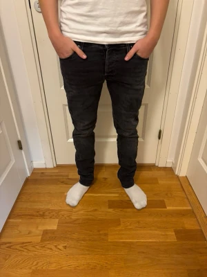 Svarta slim fit jeans herr - Säljer ett par svarta slim fit jeans med klassisk femficksmodell och normal midja. Jeansen har smal passform hela vägen ner och är tillverkade i ett stretchigt material för extra komfort. Perfekta för en avslappnad och trendig look.