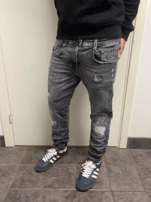 Replay anbass jeans slitningar - Riktigt feta Replay Anbass jeans med slitningar i storlek 30/30. Backpatchen är borta och lite sönder vid bältet (se bild 4 och 5) annars väldigt bra skick. A=38,5CM B=97CM C=15CM. Modellen är 173cm, 64kg. Pris kan diskuteras!!