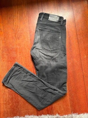 Replay Anbass Slim Fit svarta jeans - Snygga svarta jeans från Replay, modell Anbass Slim Fit. Jeansen har klassisk femficksdesign, raka ben och är tillverkade i ett stretchigt material för extra komfort. Perfekta för dig som gillar en smalare passform och stilren look.