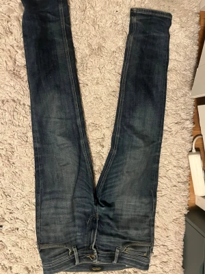 Mörkblå slim fit jeans - Snygga mörkblå slim fit jeans med klassisk femficksdesign och lätt slitna detaljer. Jeansen har normal midja och raka ben, perfekta för en avslappnad och trendig look. Materialet är denim i bomull med lite stretch för extra komfort.