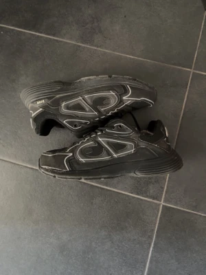 B30 - Säljer ett par svarta b30 sneakers med vita kontrastsömmar och meshpaneler. Skorna är rätt så använda med några hål som visas på bilderna. Pris kan diskuteras och skriv vid behov av bilder elr om du har frågor.