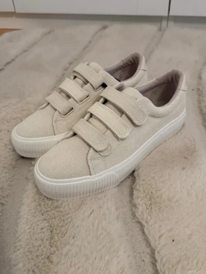 Even&Odd sneackers  - Stilrena sneakers i beige tyg med tre breda kardborreband och vit sula. Skorna har en låg profil och är tillverkade i ett ribbat textilmaterial som ger en trendig och avslappnad look. Perfekta för dig som gillar enkel och clean stil💗 Köpa från Zalando och aldrig använda pågrund av att dem är för stora💗
