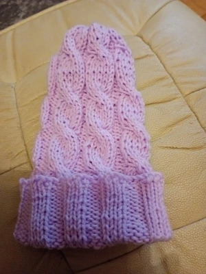 Ljuslila kabelstickad mössa - Säljer en söt ljuslila mössa med kabelstickat mönster och bred uppvikt kant. Mössan är handstickad i mjukt garn och har en klassisk, lite längre modell som ger en avslappnad look. Perfekt för dig som vill ha en mysig och trendig accessoar till hösten och vintern.