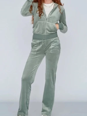 Grön velour loungewear-set - Mysigt loungewear-set i mjuk grön velour med dragkedja på hoodien och resår i midjan på byxorna. Setet har fickor både på överdelen och byxorna samt ribbade muddar. Perfekt för chill dagar hemma eller när du vill vara bekväm men ändå snygg.