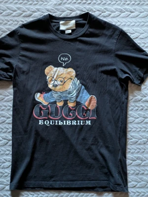Gucci Equilibrium Graphic T-Shirt - Svart bomulls-T-shirt med exklusivt Gucci Equilibrium-tryck på bröstet.