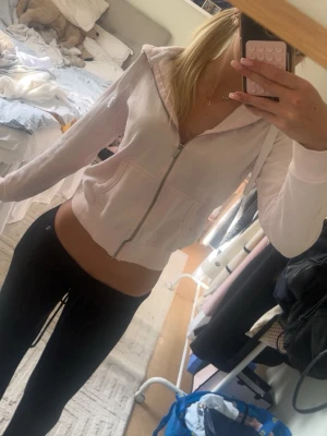 Ljusrosa hoodie med dragkedja - Säljer en ljusrosa hoodie från Tindra med dragkedja framtill och två fickor. Hoodien har huva och ribbade muddar vid ärmslut och nederkant. Perfekt för en chill och avslappnad stil. Materialet är mjukt och skönt mot huden. Russemerch liknande