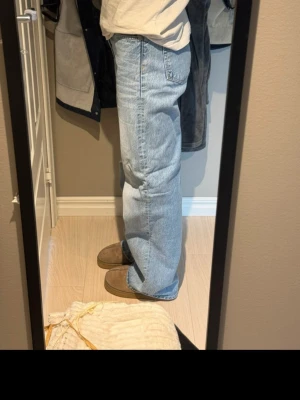 Ljusblå raka jeans - Säljer ett par ljusblå jeans med rak passform och klassisk femficksdesign. Jeansen har hög midja och är tillverkade i ett mjukt denimtyg som ger en avslappnad look. Perfekta för dig som gillar en enkel och tidlös stil.
