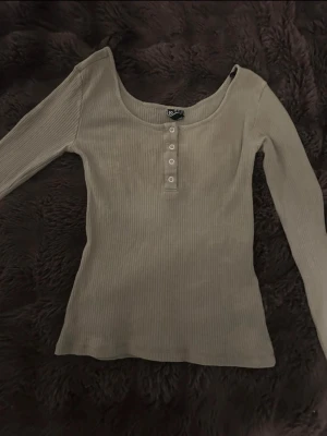 Grön ribbad långärmad topp - Väldigt fin grön  ribbad topp med lång ärm och rundad urringning från Pieces i storlek M 🥰 Knappar framtill och stretchigt material. Tröjan har små blekta fläkar framtill, men annars i väldigt bra skick!