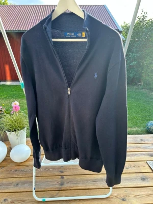 Mörkblå ziptröja från Polo Ralph Lauren - Klassisk mörkblå ziptröja från Polo Ralph Lauren med hög krage och diskret broderad logga på bröstet. Tröjan har långa ärmar, ribbade muddar och är tillverkad i mjukt material som passar perfekt till lager på lager. Pris ej hugget i sten kom om för frågor😁