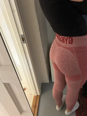 Rosa sömlösa leggings från Gymshark - Säljer ett par rosa sömlösa leggings från Gymshark med hög midja och bred resår. Materialet är stretchigt och följsamt, perfekt för träning eller chill. Snyggt mönster i olika rosa nyanser och logga i midjan. Supersköna och sitter på plats hela dagen.