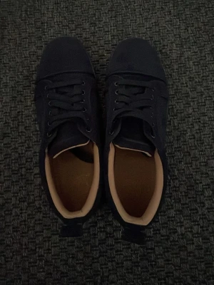 Mörkblå canvas sneakers - Snygga mörkblå sneakers i canvas med matchande mörkblå snören och diskret sula. Insidan är beige och skorna har klassisk låg profil med metallöljetter på sidan för ventilation. Perfekta för en clean och stilren look.             Ingen orginal box tillkommer!