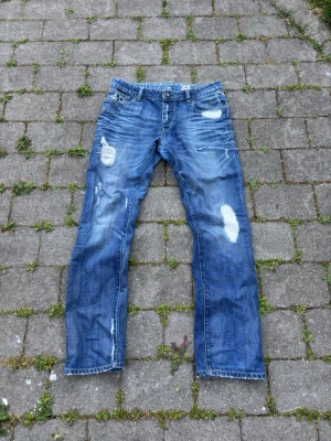 Blå archive jeans från Jack and jones  - Säljer ett var extremt snygga jeans från J&J. Väldigt snygg tvätt båda bak och fram samt unika slitage. 