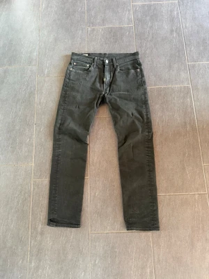 Svarta slim fit jeans - Snygga svarta slim fit jeans med klassisk femficksdesign och raka ben. Jeansen har knappgylf och detaljer i metall. Passar perfekt till en avslappnad streetwear-look och är tillverkade i ett mjukt denimtyg. Ser ej någon storlek men sitter som en 29/32 