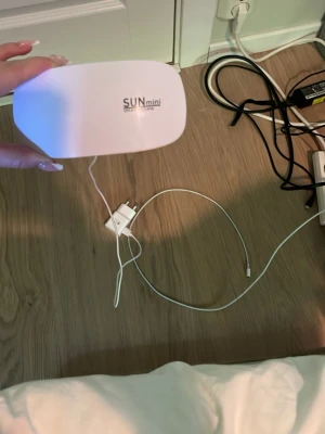 SUNmini UV LED lampa för naglar - Praktisk och smidig UV LED-lampa från SUNmini i vit plast. Perfekt för att härda gel- och shellacknaglar hemma. Kompakt design med sex LED-lampor och USB-sladd för enkel anslutning. Lätt att ta med och använda när du fixar naglarna.
