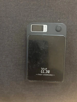 Svart powerbank 22.5W snabbladdning - En svart powerbank med 22.5W snabbladdning och digital display. Kompakt och rektangulär design med rundade hörn. Tillverkad i plast och har en kapacitet på 20000mAh enligt märkning på baksidan. Perfekt för att ladda mobilen snabbt när du är på språng.