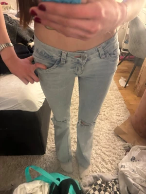 Nelly stich ljusblåa jeans - Säljer ett par ljusblå bootcut jeans med slitningar vid knäna och klassisk femficksmodell. Jeansen har låg midja och är i stretchigt denimtyg. Nästan aldrig använda, kommer aldrig till användning därav att jag säljer jag dom 