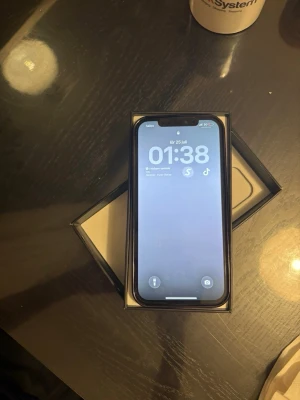 iPhone 12 Pro Max - Säljer en vit iPhone med stilren design och trippelkamera på baksidan. Telefonen har en platt framsida med tunn ram och glasbaksida. Perfekt för dig som gillar snygg och modern teknik det ingår skärm skydd magsafe skal och laddare