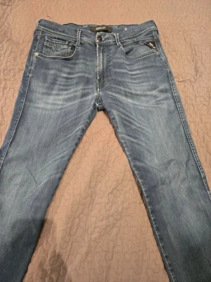 Replay anbass - Snygga blå jeans från Replay med klassisk femficksdesign och diskreta slitningar framtill. Jeansen har normal midja, raka ben och tydliga kontrastsömmar. Perfekta för en avslappnad och trendig stil.