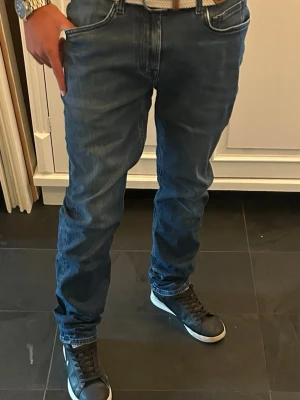 Slimfit jeans Dressmann - Säljer ett par mörkblå jeans med slim fit och klassisk femficksdesign. Jeansen har snygga kontrastsömmar och normal midja. Perfekta till vardagslooken och passar till det mesta. Materialet är denim i bomull.