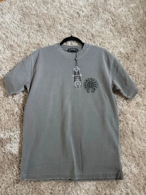 Chrome hearts t-shirt  - Säljer en chrome hearts t-shirt i snygg färg, tröjan är i storlek S och sitter snyggt och avslappnat, cool design på ryggen 