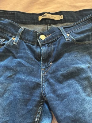Blå lågmidjade raka jeans  - Snygga blå jeans med rak passform och klassisk femficksdesign. Jeansen har en knappgylf och bälteshällor, samt kontrastsömmar. Perfekta för en avslappnad och stilren look. Modellen är " Straight men låg midja och har en tidlös blå tvätt.