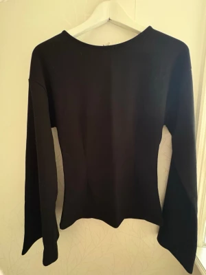 Svart långärmad topp från Nelly - En enkel och stilren svart långärmad topp från Nelly. Toppen har en rund halsringning och är figurnära i modellen, vilket ger en snygg siluett. Perfekt att matcha med jeans eller kjol för en clean look.