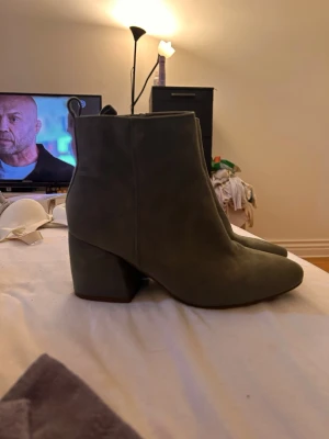 Mörkgröna mocka stövletter med klack - Snygga mörkgröna stövletter i mocka med bred klack och spetsig tå. Dragkedja på insidan för enkel påtagning. Perfekta till höstens outfits och ger en trendig touch till din stil.