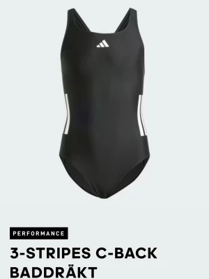 Svart baddräkt med vita ränder Adidas - Snygg svart baddräkt från Adidas med klassiska vita 3-stripes på sidorna och Adidas-logga framtill. Modellen har breda axelband och C-back för bra stöd. Tillverkad i ett stretchigt material som passar perfekt för simning och träning.