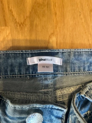 Blå slitna bootcut jeans Gina Tricot - Säljer ett par blå bootcut jeans från Gina Tricot i storlek XS. Jeansen har slitningar och hål på knäna för en trendig look, klassisk femficksmodell och knappgylf. Lite utstreatcheade och slitningarna är lite sönder men ändå i fint skick. Därför priset!