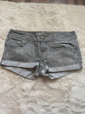 Grå denimshorts med uppvik - Ett par grå Lågmidjade jeansshorts från American eagle 2000-tal. 