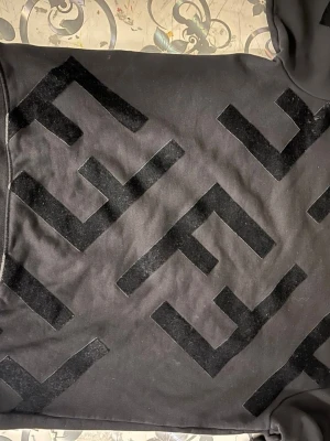 Fendi tröja  - Cool svart sweatshirt med stora, svarta sammetsliknande logotypmönster över hela framsidan. Tröjan har en avslappnad passform och är tillverkad i mjukt bomullsmaterial. Perfekt för dig som gillar streetwear och vill sticka ut.