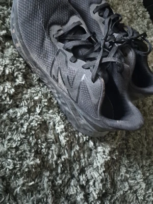 Svarta New Balance sneakers - Snygga svarta sneakers från New Balance med mesh-överdel och stora NB-loggor på sidorna. Skorna har tjock sula och klassisk snörning. Perfekta för dig som gillar sportig och stilren look. De är bra att tvätta dem innan andvändning