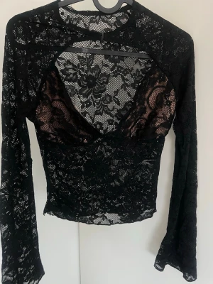 Svart långärmad topp i choker stil  - Snygg svart topp i genombruten spets med blommigt mönster.