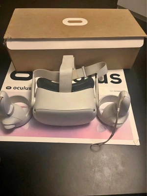 Oculus quest 2 - Säljer ett par Oculus VR-glasögon i vit plast med justerbart tygband och två matchande handkontroller. Perfekt för gaming och VR-upplevelser. Levereras med originalkartong och tillbehör som syns på bilden.