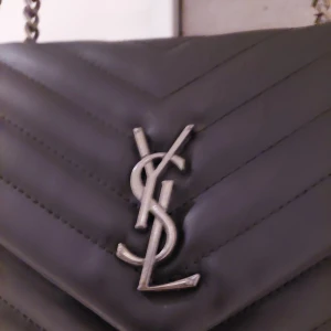 Ysl kp ny  - Ysl ny kp väska med 2 fack + 1 med dragkedja + 2 små sidofack i väskan, Rejala kedjor, 500kr obs inget i väskan  Då många skicka om att vilja har bild när jag har den på så har jag lagt ut en bild, (ej äkta)