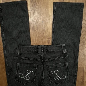 Lågmidjade bootcutjeans med rhinestone detaljer - Säljer dessa gråa bootcutjeans med  rhinestone detaljer i storlek 34 💘  Midjemått: 73 cm Innerbenslängd: 68 cm 