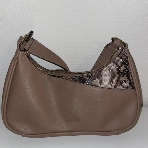 Don Donna Väska - En jättefin beige väska från märker Don Donna. Lite längre band och i nyskick! 