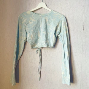 Croptop från Weekday - CropTop från Weekday med öppen rygg. Ljusblått-vitt mönster. Använd en gång. Bekväm passform, bekväm att bära utan bh trots öppen rygg/sida.  