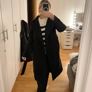 Lång svart kappa - Säljes för jag har en annan likadan. Använd fåtal gånger och är i nyskick. Kappan är lång och har både knyte och knappar för att stänga den👌🏻lite liten i storlek, jag bär vanligtvis M och fick gå upp en storlek💕 Nypris: ca 500kr