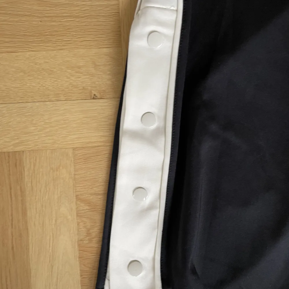 Svarta byxor från H&M med vit linje på sidbenet. De har dragsko och två fickor. De har även knappar i slitsen. Innerbens sömmen är 73cm. Aldrig använda, helt nytt skick. Jeans & Byxor.