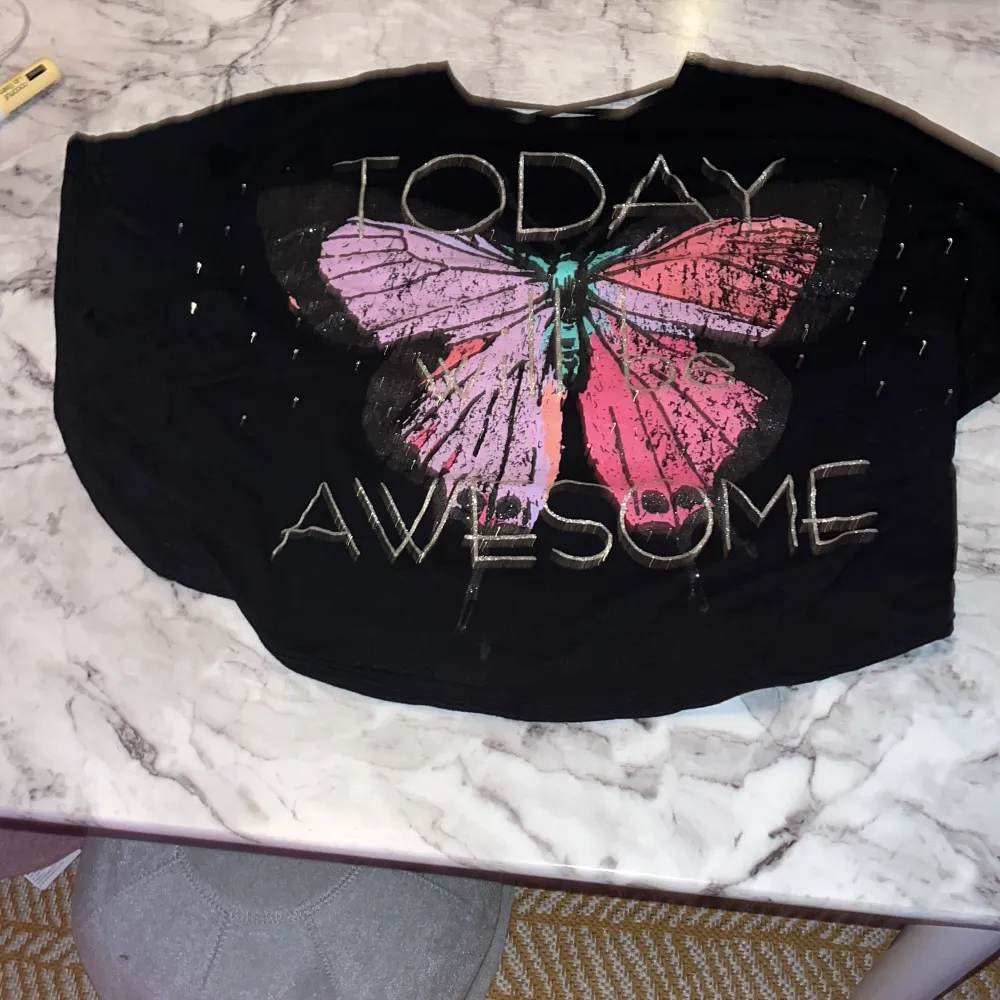 En t-shirt med fjärilar o glitter på, på baksidan så e det några sträck. T-shirts.