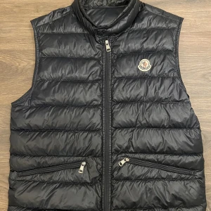 Moncler Gui Vest - Moncler Gui Vest i kanon skick, endast en lagning på baksidan men inget som syns vid användning. Storlek 2 = S/M i mörkblå. Bara att skriva vid frågor och funderingar :)