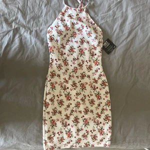 Nelly klänning - Jättefin blommig tight klänning från Nelly.com som inte finns att köpa längre. Aldrig använt så alla lappar sitter kvar. Öppen rygg.