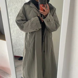 Trenchcoat  - Säljer en jättesnygg Grön/Grå trenchcoat. Perfekt till våren och kalla sommarkvällar☀️. Strl 44 men skulle säga att den passar de flesta storlekarna beroende på hur man vill att den ska sitta. Märket är Kappahl! Hör av dig vid fler frågor eller bilder🌸