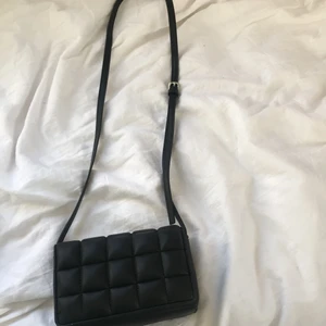 Svart väska från hm  - En svart väska från hm som jag köpte i slutet av sommaren 2021!☀️💓😍 Har aldrig använt den, den har bara hängt på en krok ett tag. Säljer pga att den inte kommer till användning.❤️❤️köpt för 149kr!