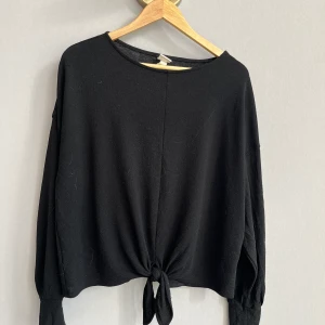 Tröja med knut  - Svart tröja i skönt material med knut nertill