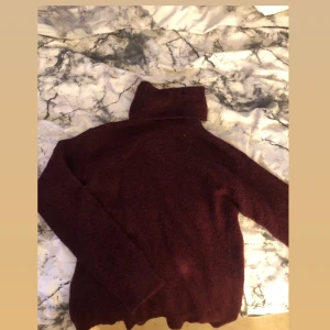 Stickad tröja - Den är inte särskilt tjock i materialet men den är superfin och har krage som du kan vika efter din anpassning! Det står att storleken är Xs, men jag skulle uppskatta den till S om inte till och med M. Vinröd.