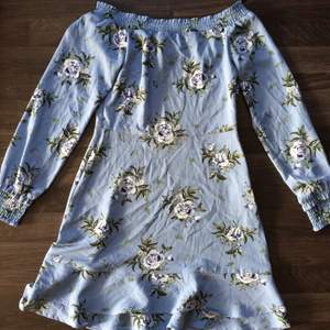 Blå blommig klänning från H&M i nyskick. Klänningen är i storlek 36 är och of shoulder.