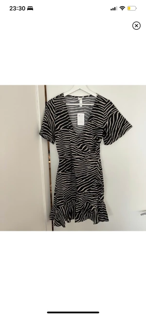 Klänning 36 - Kollar intresset för denna då jag har så många klänningar. Strl 36 från H&M. Stängs med två knappar i midjan(en dold på insidan), finns en hak-knapp vid brösten. Zebra mönster i svart och beige. Oanvänd och felfri! 