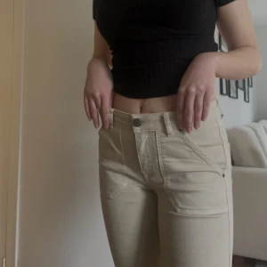 Beige Jeans - Beiga jeans som knappt är använda! Kapad bootcut med lite fransar och medelhög midja. Inköpt förra sommaren för 699:-. Passar mig som är mellan 34 o 36 i strl. 